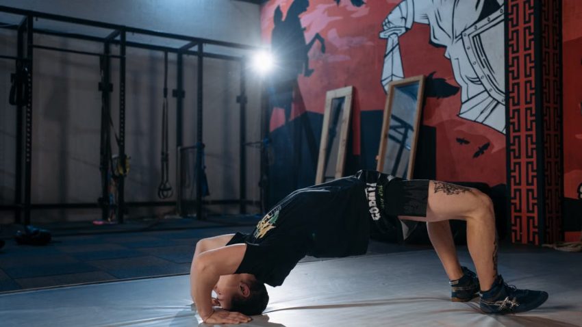Man performing a back bridge stretch in a gym, emphasizing flexibility and fitness.